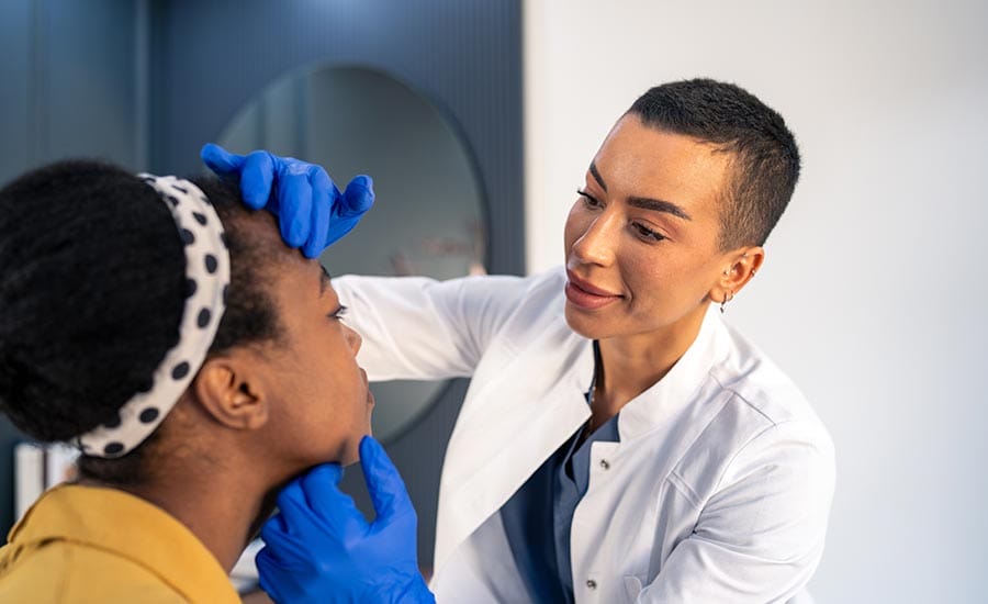 A treatment specialist checking a young woman's face​