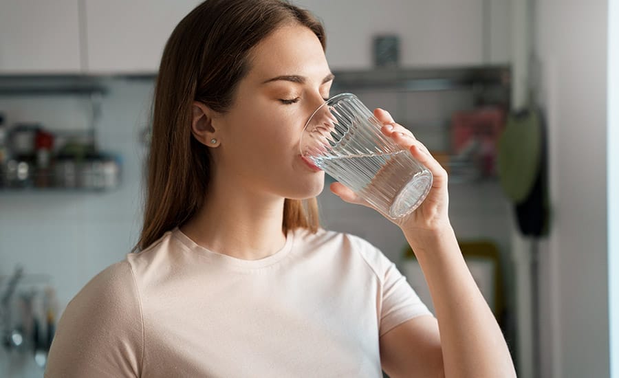 A young woman drinking a glass of water​