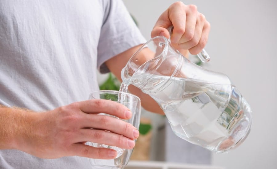 A young man pouring a glass of water​