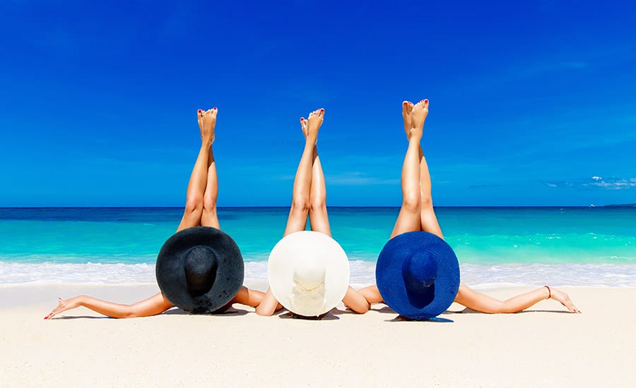 Three young women wearing hats in the beach​