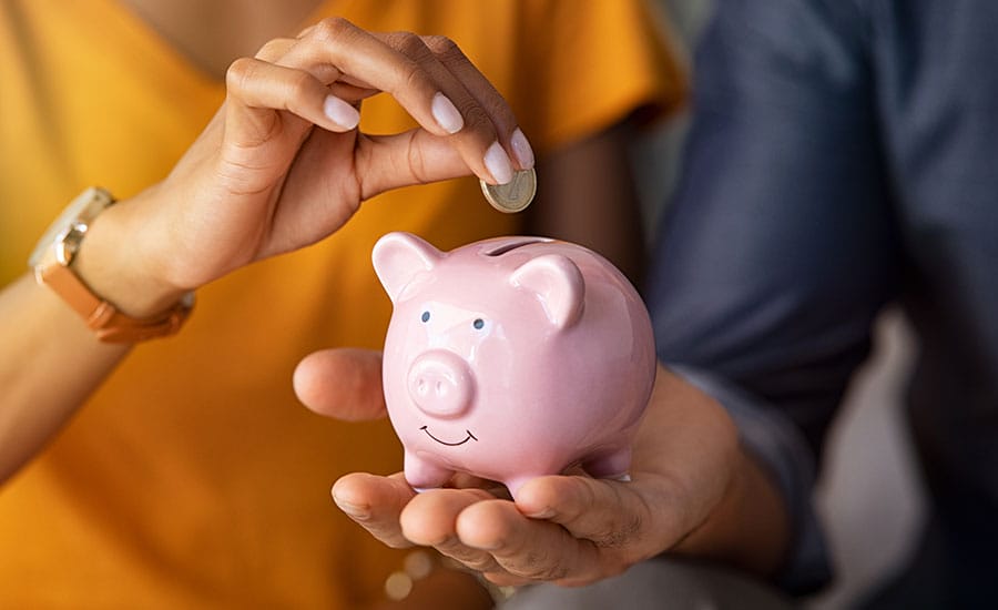 A young woman inserting a coin into a piggy bank